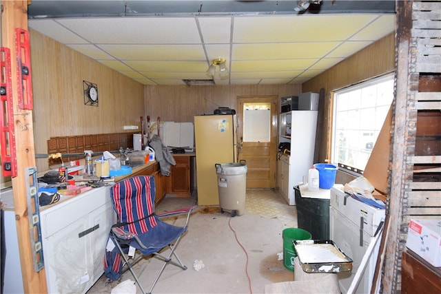 kitchen featuring wood walls, fridge, and a paneled ceiling