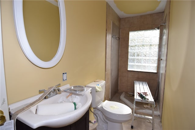 bathroom featuring vanity, toilet, tile patterned floors, and tiled shower