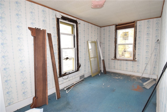 carpeted spare room featuring crown molding