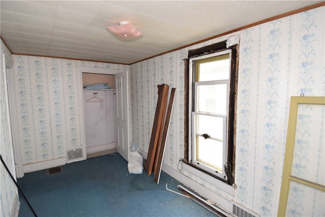 unfurnished bedroom with ornamental molding, carpet, multiple windows, and a closet