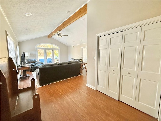 living room with ceiling fan, light hardwood / wood-style flooring, lofted ceiling with beams, and a textured ceiling