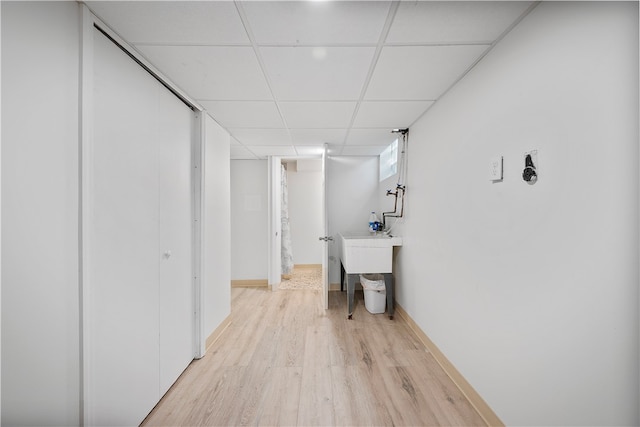 basement with a drop ceiling and light hardwood / wood-style flooring