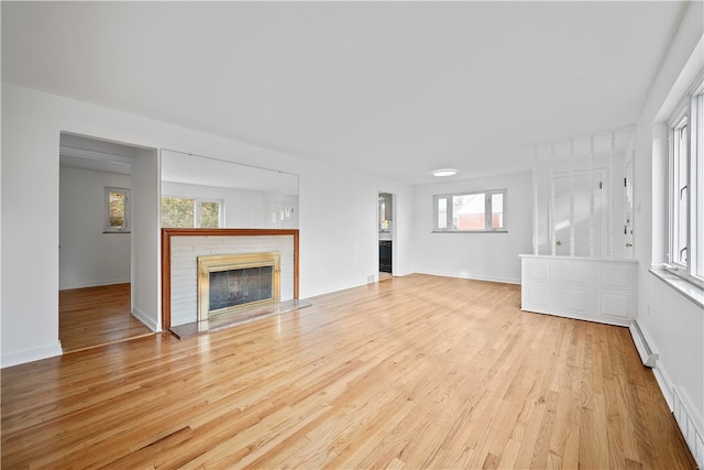 unfurnished living room with a baseboard radiator, light hardwood / wood-style floors, and plenty of natural light