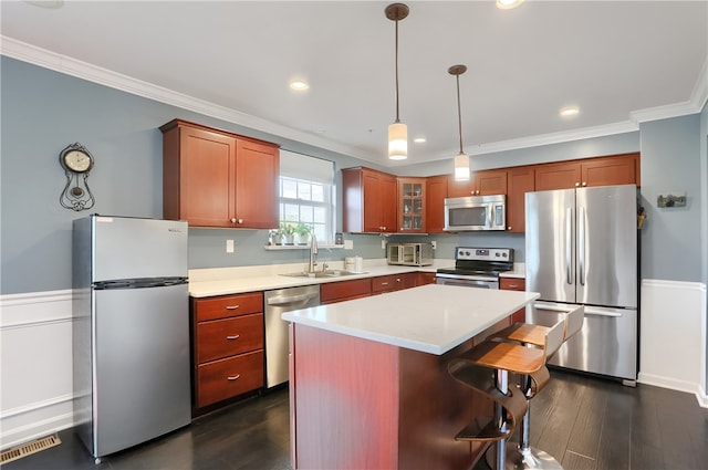 kitchen with sink, a kitchen island, stainless steel appliances, ornamental molding, and dark hardwood / wood-style floors