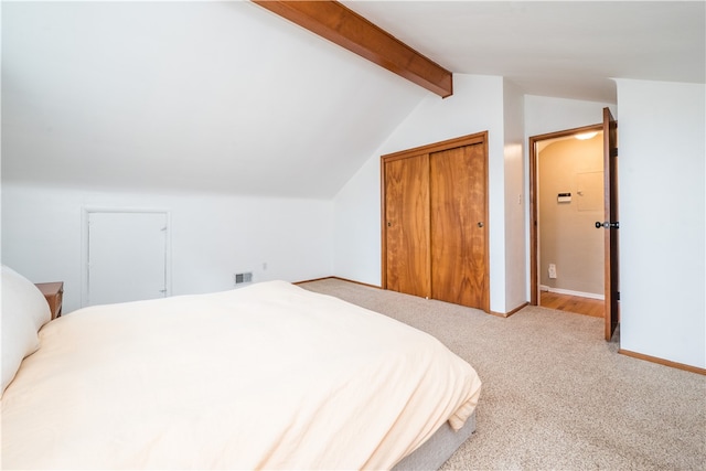 carpeted bedroom with a closet and vaulted ceiling with beams