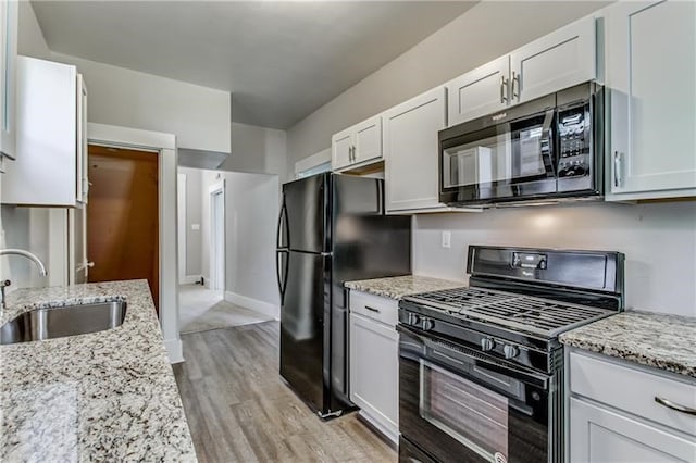 kitchen featuring sink, black appliances, light wood-type flooring, white cabinetry, and light stone counters