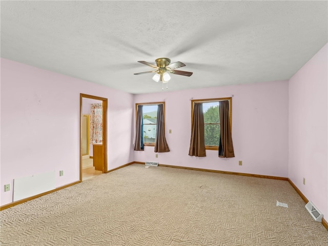 carpeted spare room featuring a textured ceiling and ceiling fan