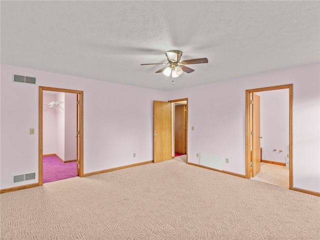 spare room with a textured ceiling, light colored carpet, and ceiling fan