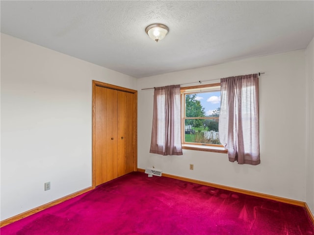 unfurnished bedroom with carpet, a textured ceiling, and a closet