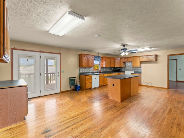 kitchen featuring a textured ceiling, white dishwasher, a center island, light hardwood / wood-style floors, and ceiling fan