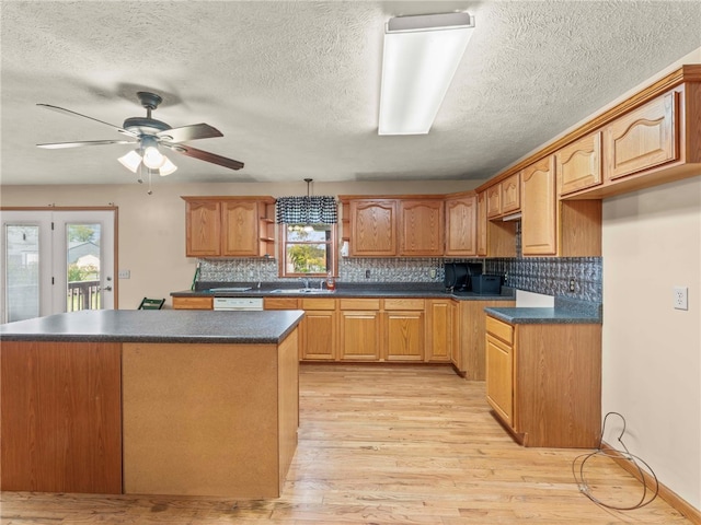 kitchen featuring sink, a textured ceiling, decorative backsplash, and light hardwood / wood-style flooring