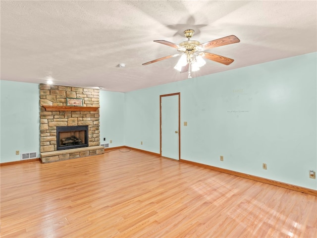 unfurnished living room with ceiling fan, a textured ceiling, light wood-type flooring, and a fireplace