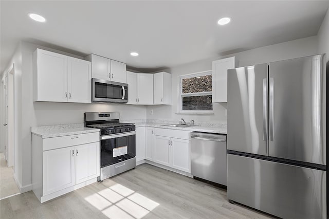 kitchen featuring sink, white cabinets, stainless steel appliances, and light wood-type flooring