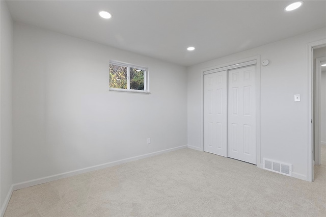 unfurnished bedroom featuring light carpet and a closet