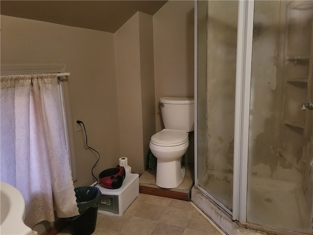 bathroom with a shower with door and toilet