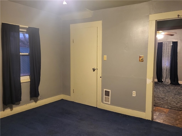 empty room with dark colored carpet and ceiling fan