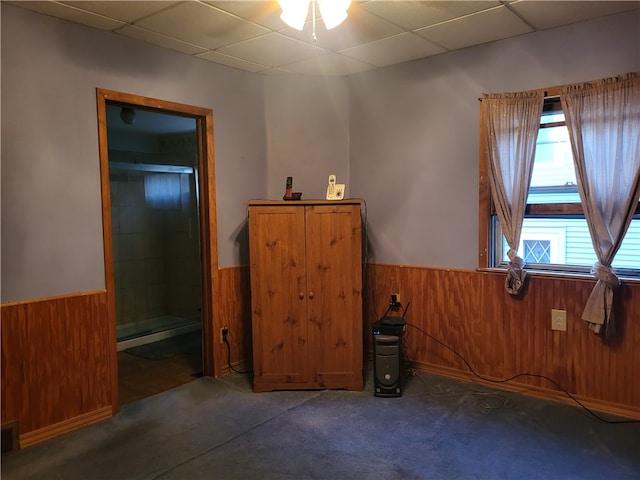 interior space featuring a drop ceiling and wood walls