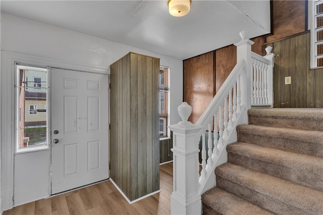 entryway featuring light wood-type flooring and wood walls