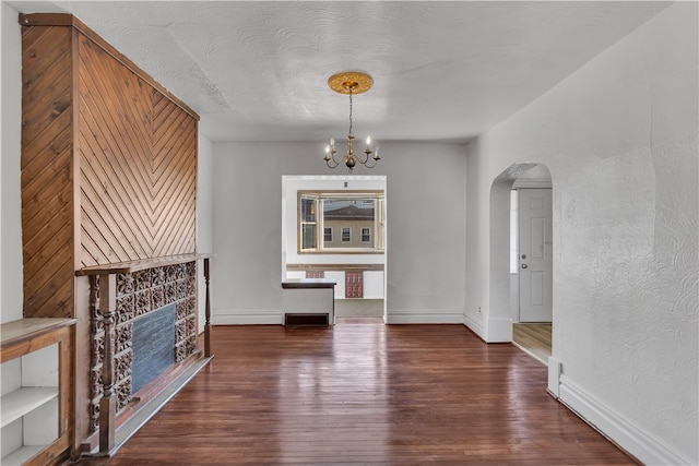 unfurnished dining area with a textured ceiling, dark hardwood / wood-style floors, and an inviting chandelier