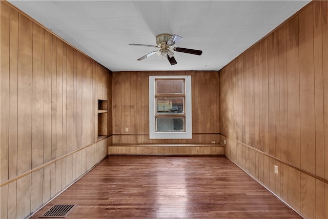 spare room with hardwood / wood-style floors, ceiling fan, and wooden walls