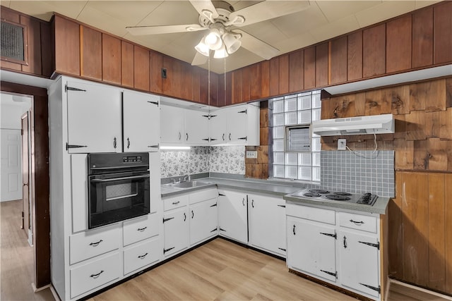 kitchen with light hardwood / wood-style flooring, black oven, white electric cooktop, white cabinets, and tasteful backsplash