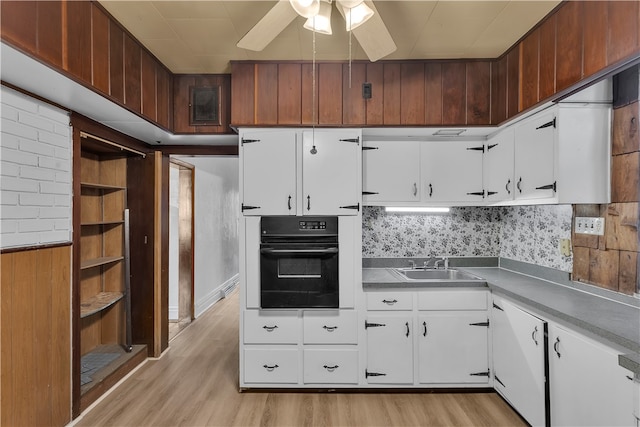 kitchen with oven, light wood-type flooring, white cabinetry, ceiling fan, and decorative backsplash