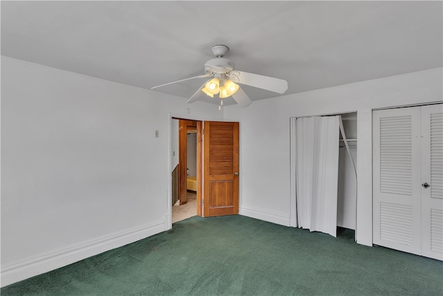 unfurnished bedroom featuring multiple closets, dark colored carpet, and ceiling fan