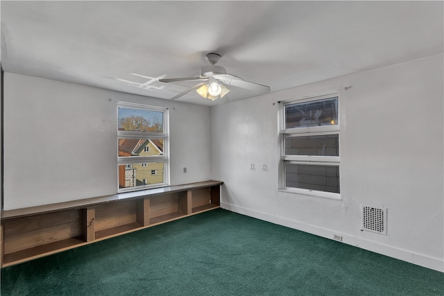 spare room featuring ceiling fan and dark colored carpet