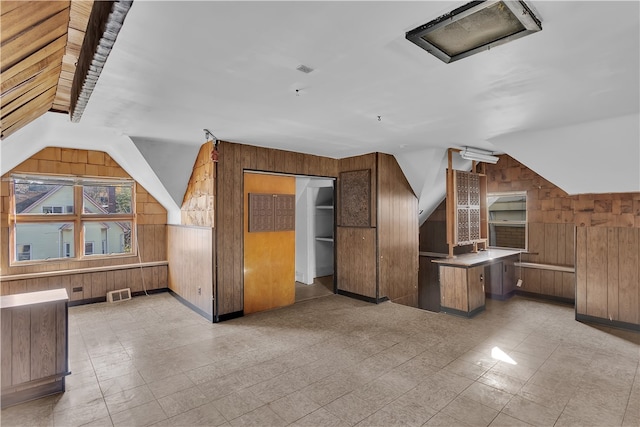 bonus room with wooden walls and vaulted ceiling