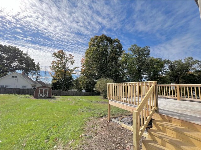 view of yard featuring a wooden deck and a storage shed