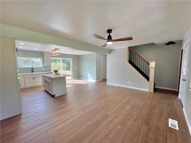 kitchen with white cabinets, light hardwood / wood-style floors, hanging light fixtures, and sink