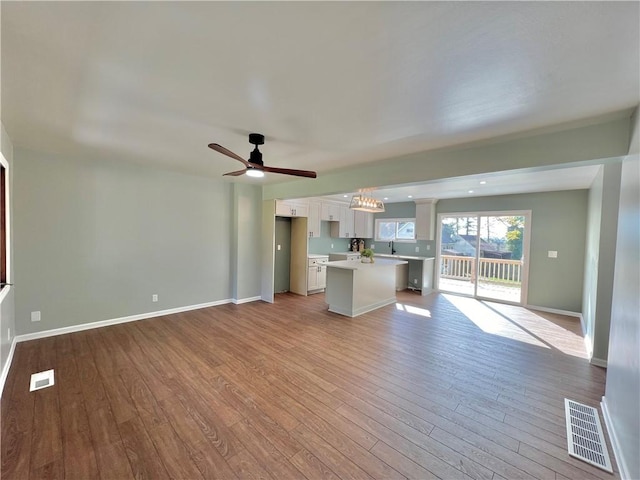 unfurnished living room featuring light wood-type flooring, ceiling fan, and sink