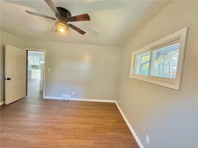 spare room featuring light wood-type flooring, washer / clothes dryer, and ceiling fan