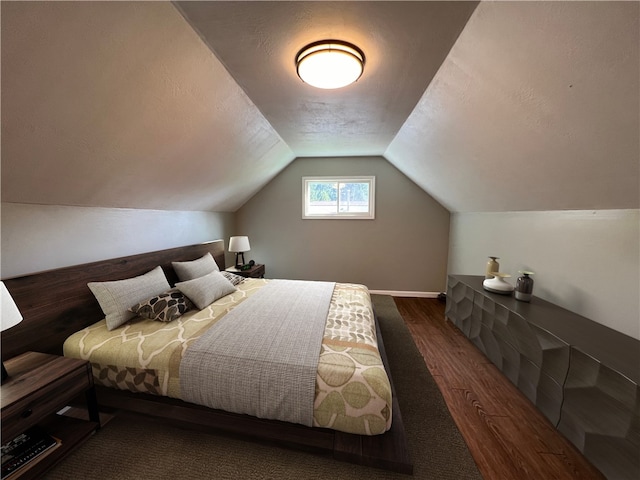 bedroom with a textured ceiling, dark hardwood / wood-style flooring, and vaulted ceiling