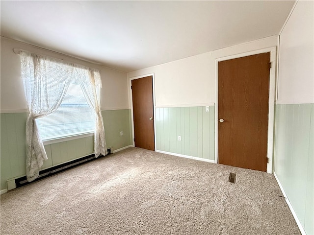 carpeted empty room featuring a baseboard radiator