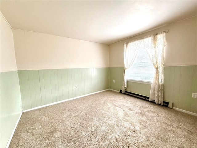 empty room with wood walls, a baseboard heating unit, and carpet