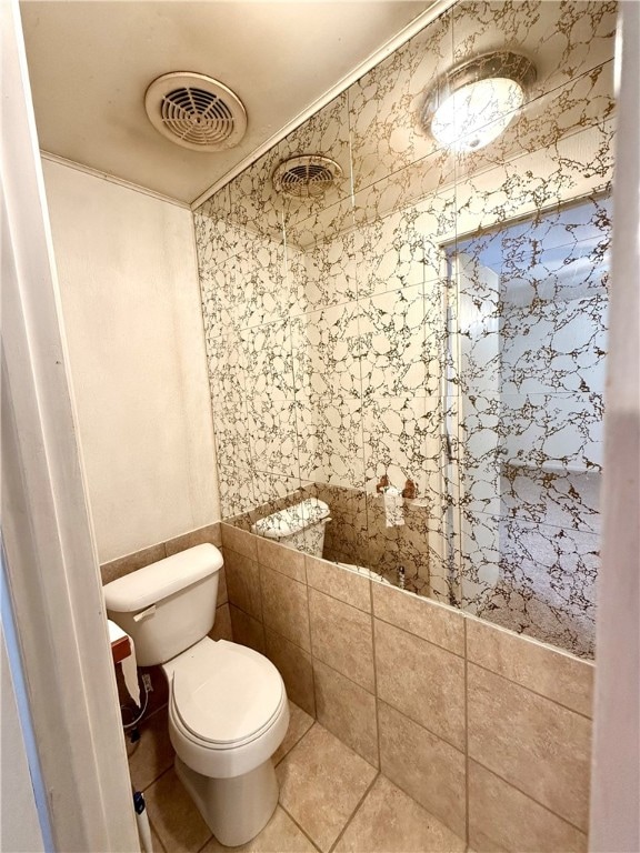 bathroom featuring toilet, crown molding, tile walls, and tile patterned flooring