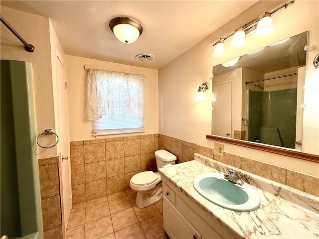 bathroom featuring a shower, tile walls, toilet, vanity, and tile patterned floors