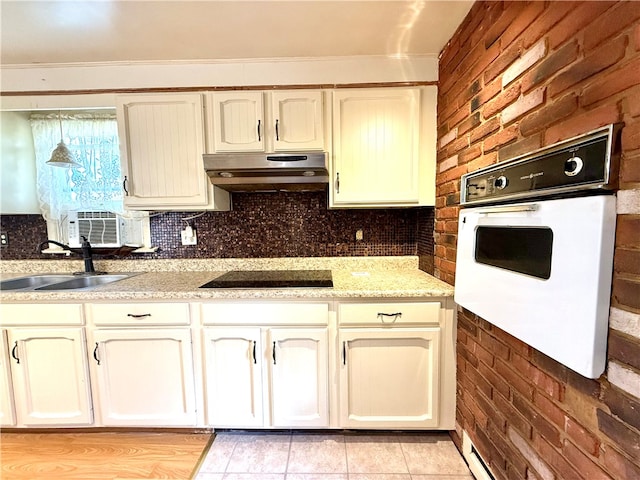 kitchen featuring light tile patterned flooring, cream cabinetry, sink, white oven, and black electric cooktop