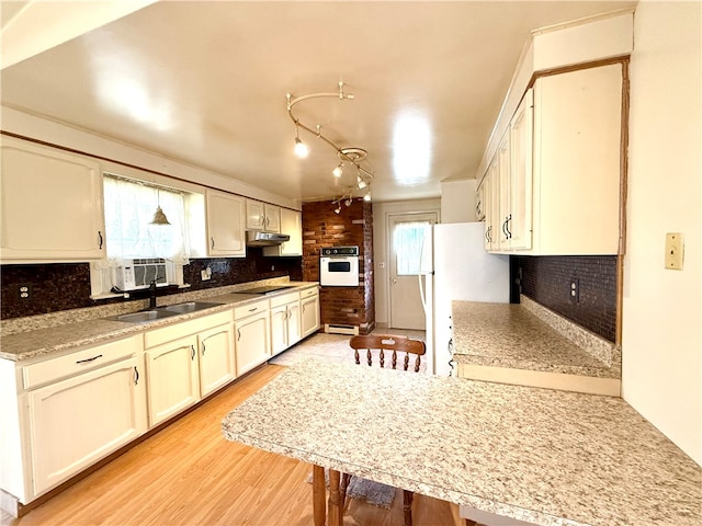 kitchen with white appliances, light hardwood / wood-style floors, tasteful backsplash, and sink