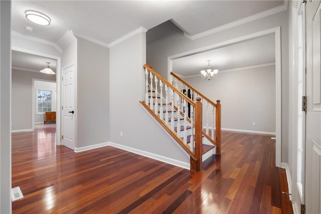 staircase featuring crown molding, wood-type flooring, and an inviting chandelier