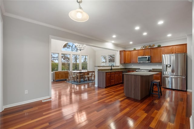 kitchen with kitchen peninsula, dark hardwood / wood-style flooring, a kitchen bar, pendant lighting, and stainless steel appliances