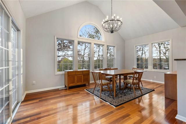 dining room with hardwood / wood-style floors, high vaulted ceiling, and a chandelier