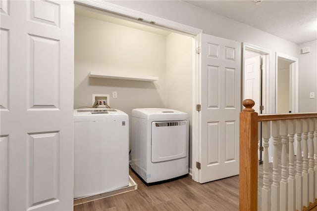 clothes washing area with separate washer and dryer and light wood-type flooring