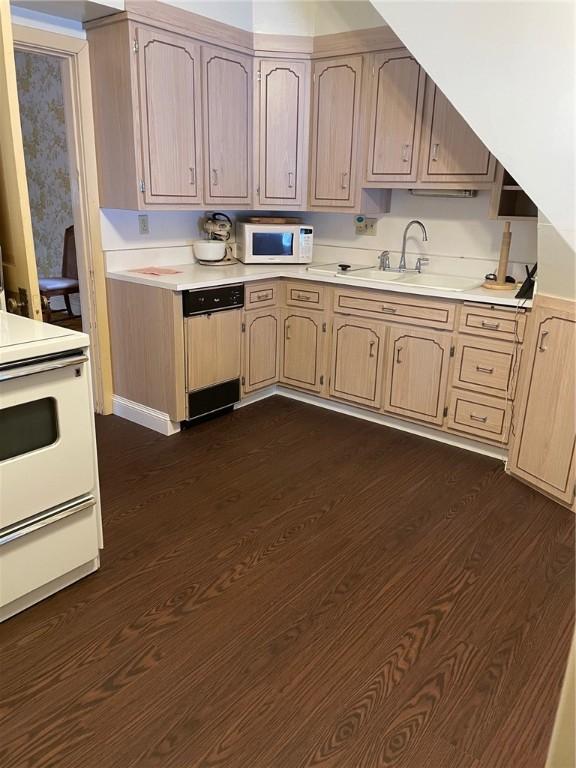 kitchen with light brown cabinetry, dark hardwood / wood-style flooring, sink, and white appliances