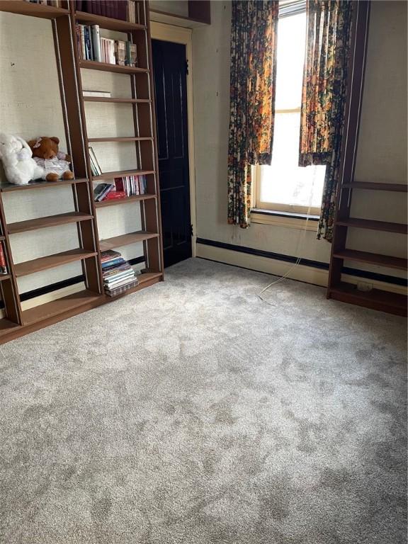 unfurnished living room featuring a baseboard radiator and carpet