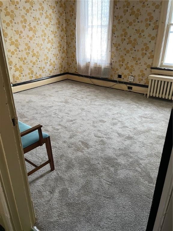 spare room featuring carpet floors and radiator heating unit