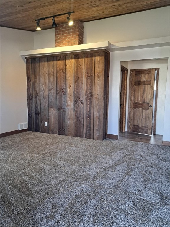 empty room with wooden ceiling, track lighting, and dark colored carpet