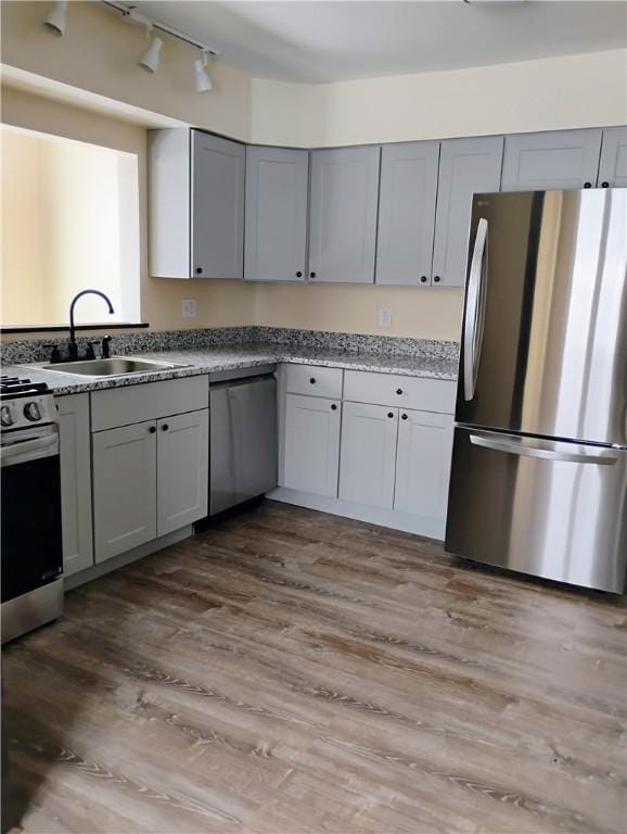 kitchen featuring wood-type flooring, stainless steel appliances, gray cabinetry, and sink