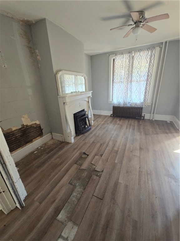 unfurnished living room featuring ceiling fan, wood-type flooring, and radiator